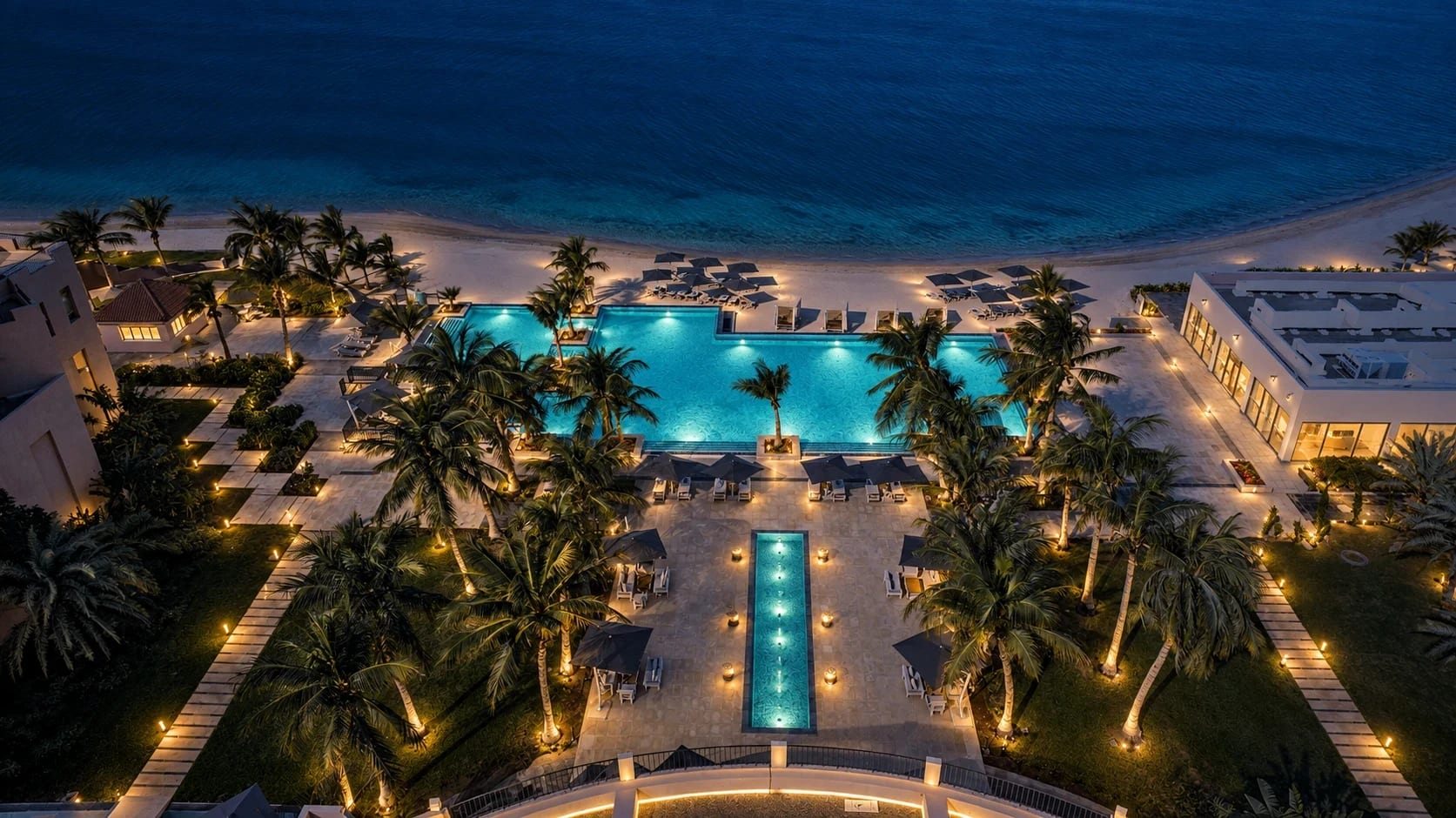 The pool terrace and beach at Sariya after dark, seen from above, with the Red Sea beyond