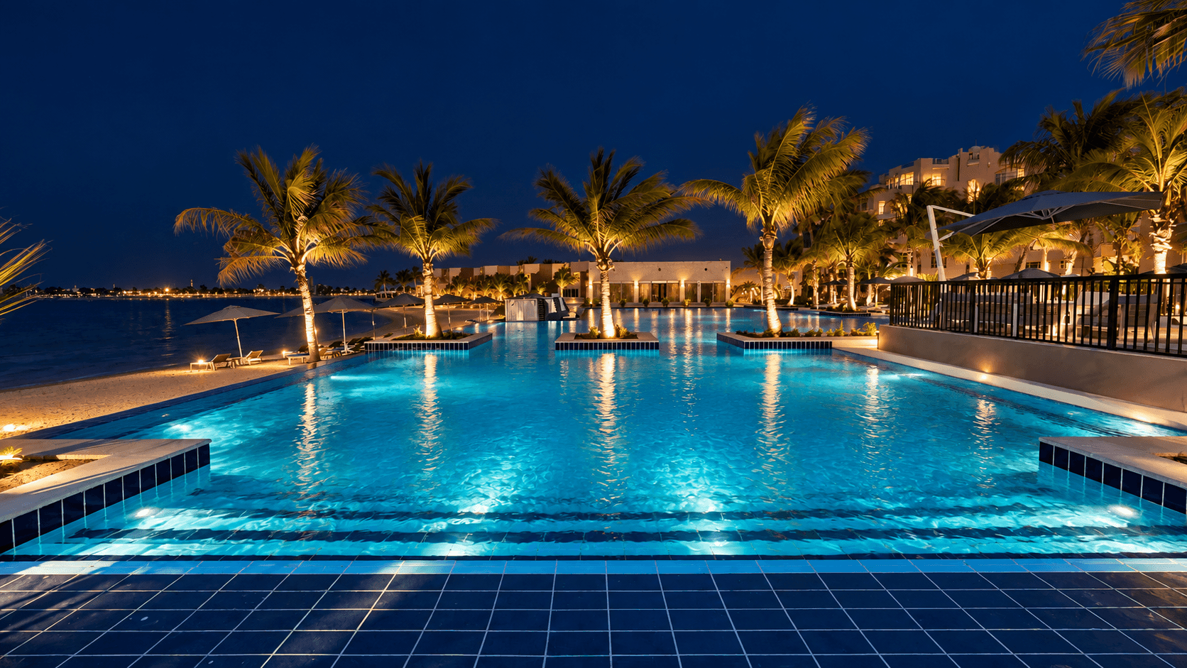 The main pool at Sariya, edged with loungers and palms, with the beach beyond